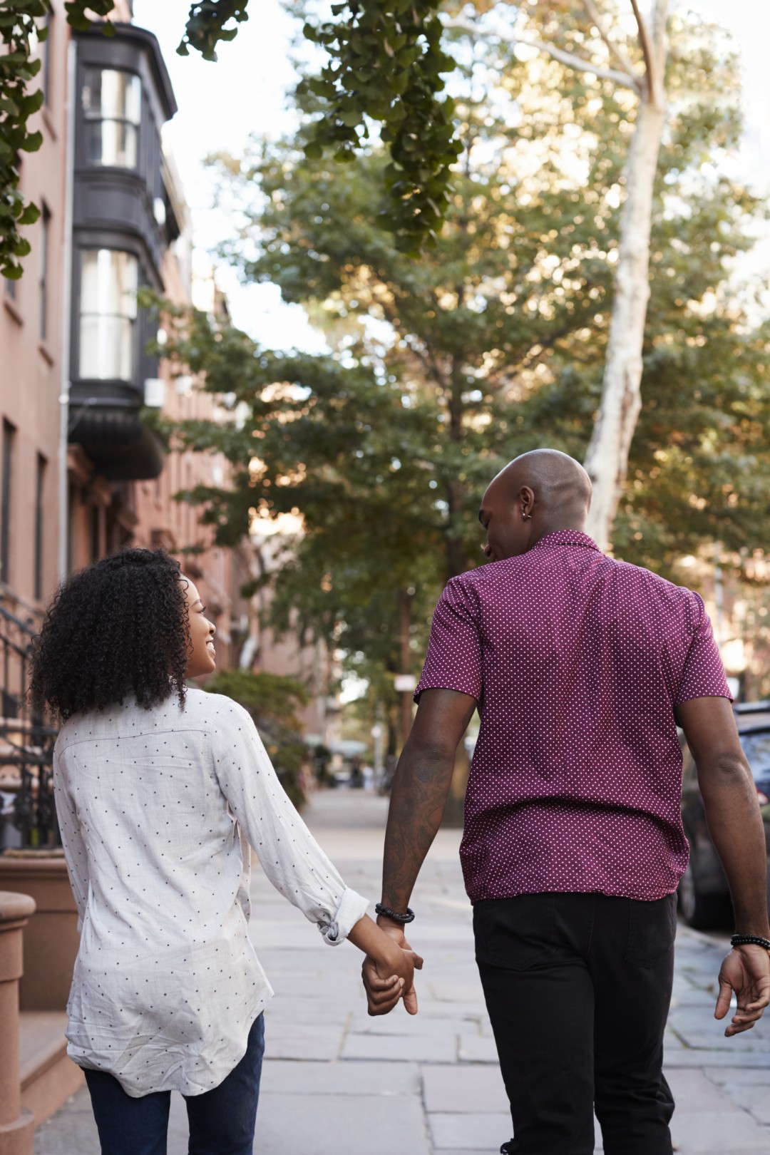 Rear View Of Couple Walking Along Urban Street In New York City
